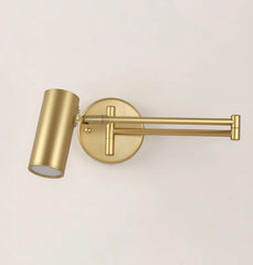 Gold-colored modern swing arm wall lamp with cylindrical shade and wall switch on white background