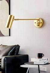 Modern gold swing arm wall lamp above black leather sofa and side table with books and black cup