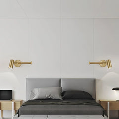 Modern bedroom with pairing gold swing arm wall sconces over gray upholstered bed with dark bedding and wooden nightstands