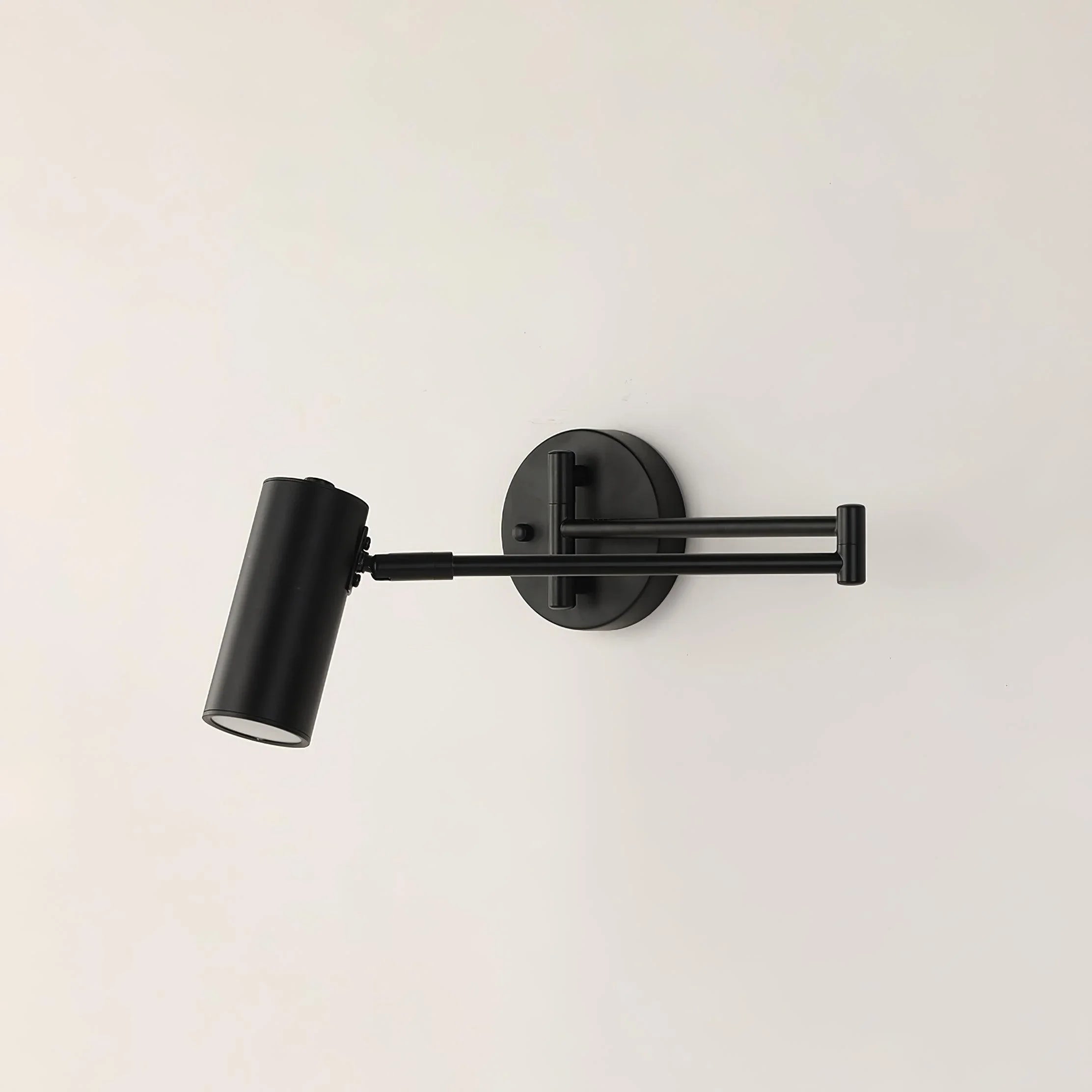Modern black swing arm wall lamp with adjustable cylindrical shade on white wall