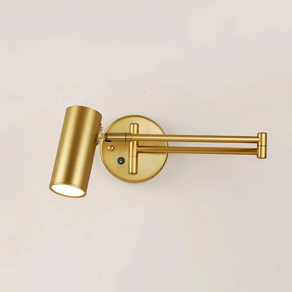 Modern gold swing arm wall lamp with cylindrical shade and wall switch on beige wall