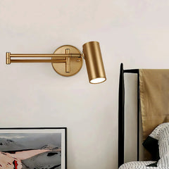 Gold swing arm wall sconce with warm light above bed and modern decor