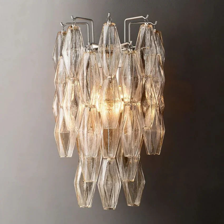 Modern Murano clear glass wall sconce with layered geometric design, illuminated on grey wall
