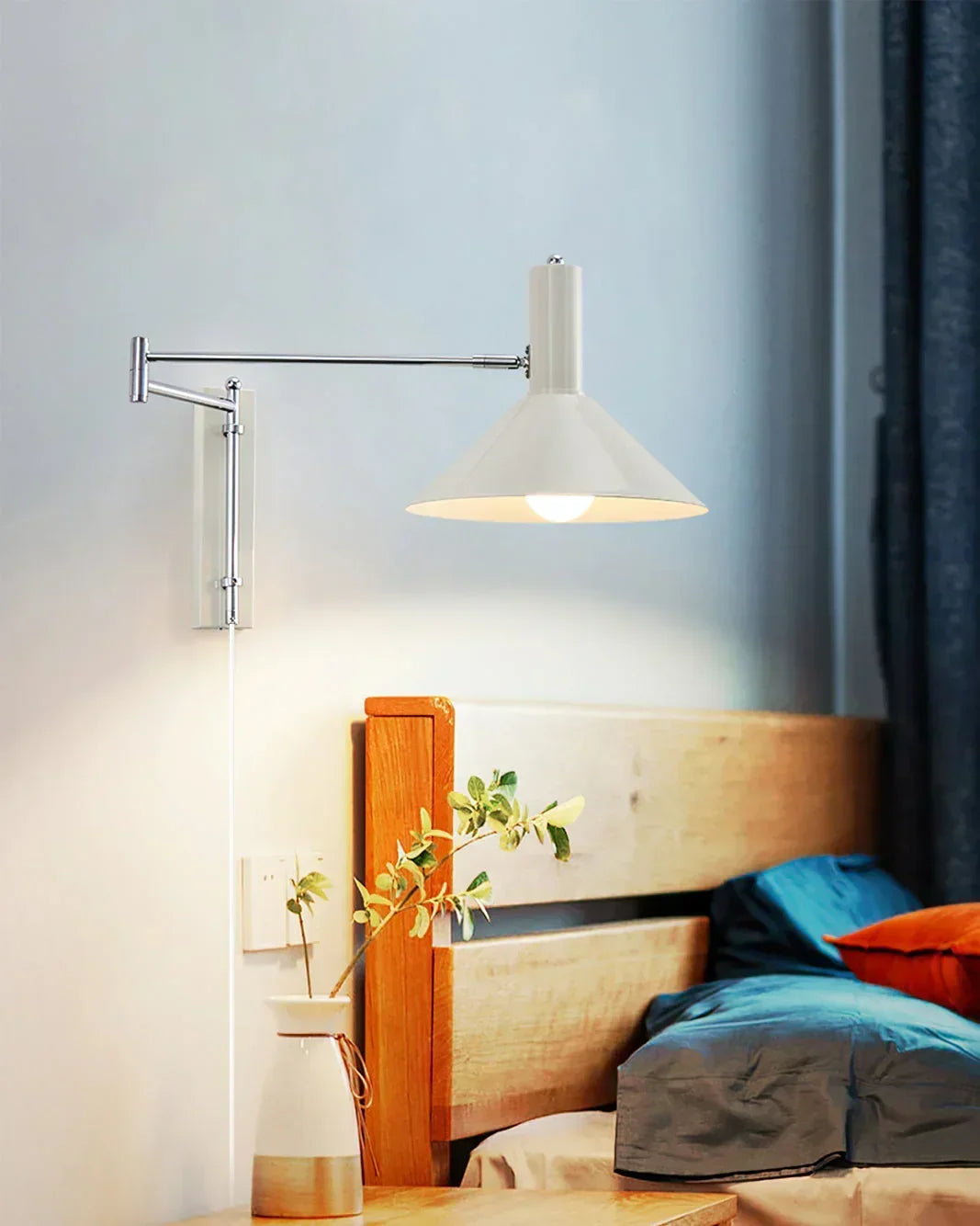 Modern white plug-in wall lamp with adjustable arm above bedside table in cozy bedroom