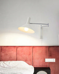 Modern white swing arm wall lamp above red upholstered headboard and nightstand