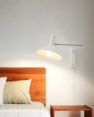 Modern white plug-in wall lamp with adjustable arm above wooden bed and nightstand