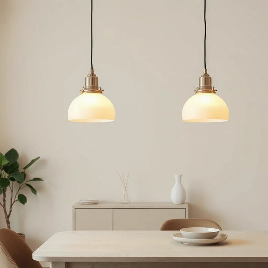 Creamy alabaster pendant lights glowing over a minimal dining table in a neutral room