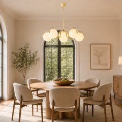 Reedway curve linear chandelier with five creamy yellow-white globe shades suspended over a modern round wooden dining table in a sunlit room - YH Lamps